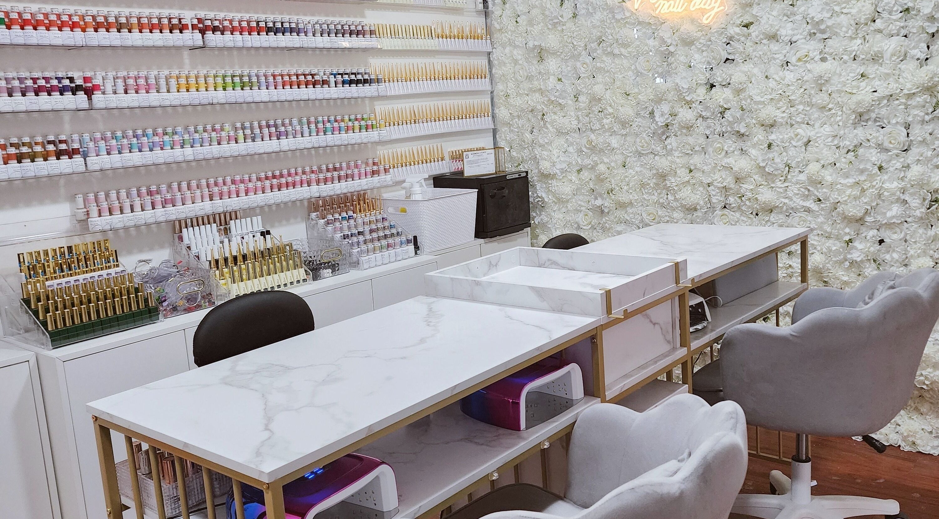 Elegant nail polish display at Vanity Nail Studio in Richmond, British Columbia, CA. Stylish workspace and floral wall.