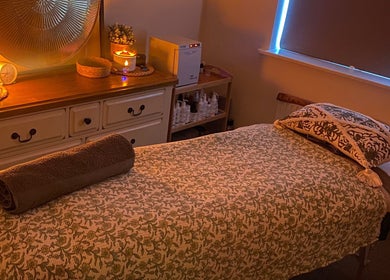 Cozy massage room at Soothing Senses, Thrapston, England, GB, featuring warm lighting and a comfortable massage table.