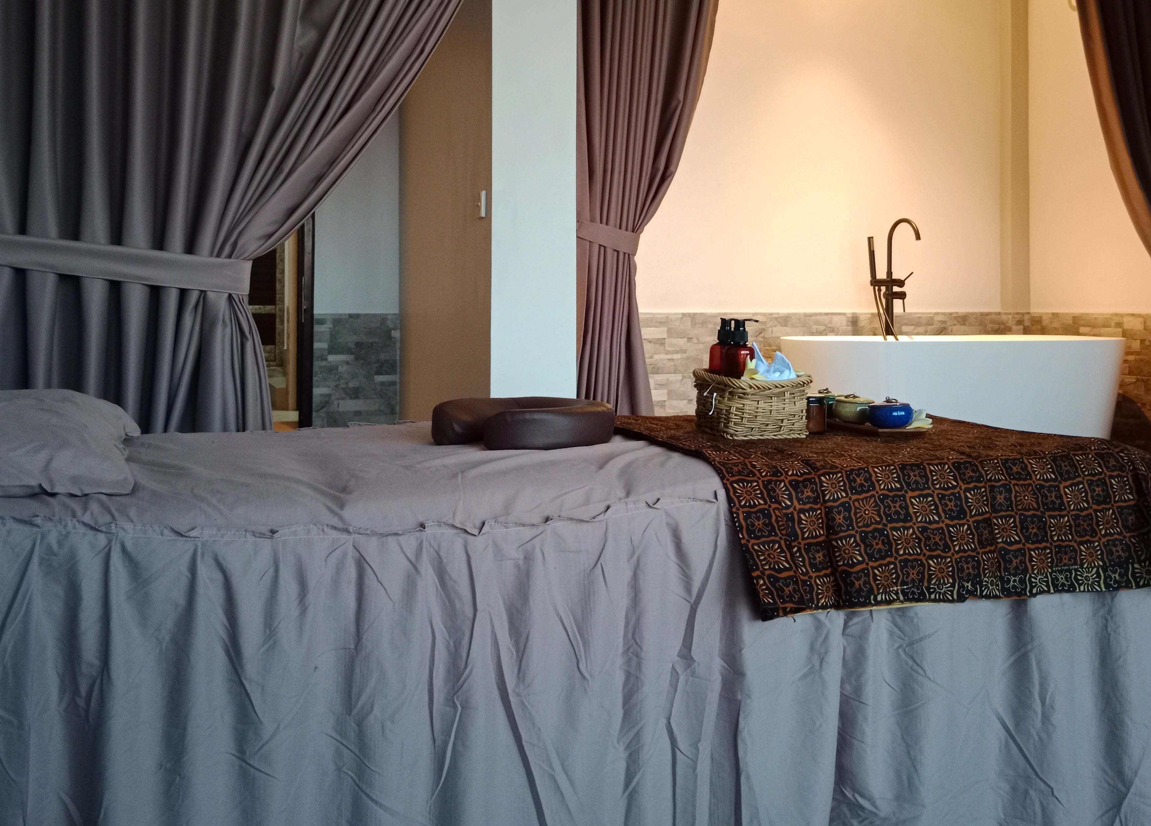 Ruang terapi di Putri Beauty and SPA Seminyak, Bali, Bali, ID dengan tempat tidur pijat dan bak mandi.