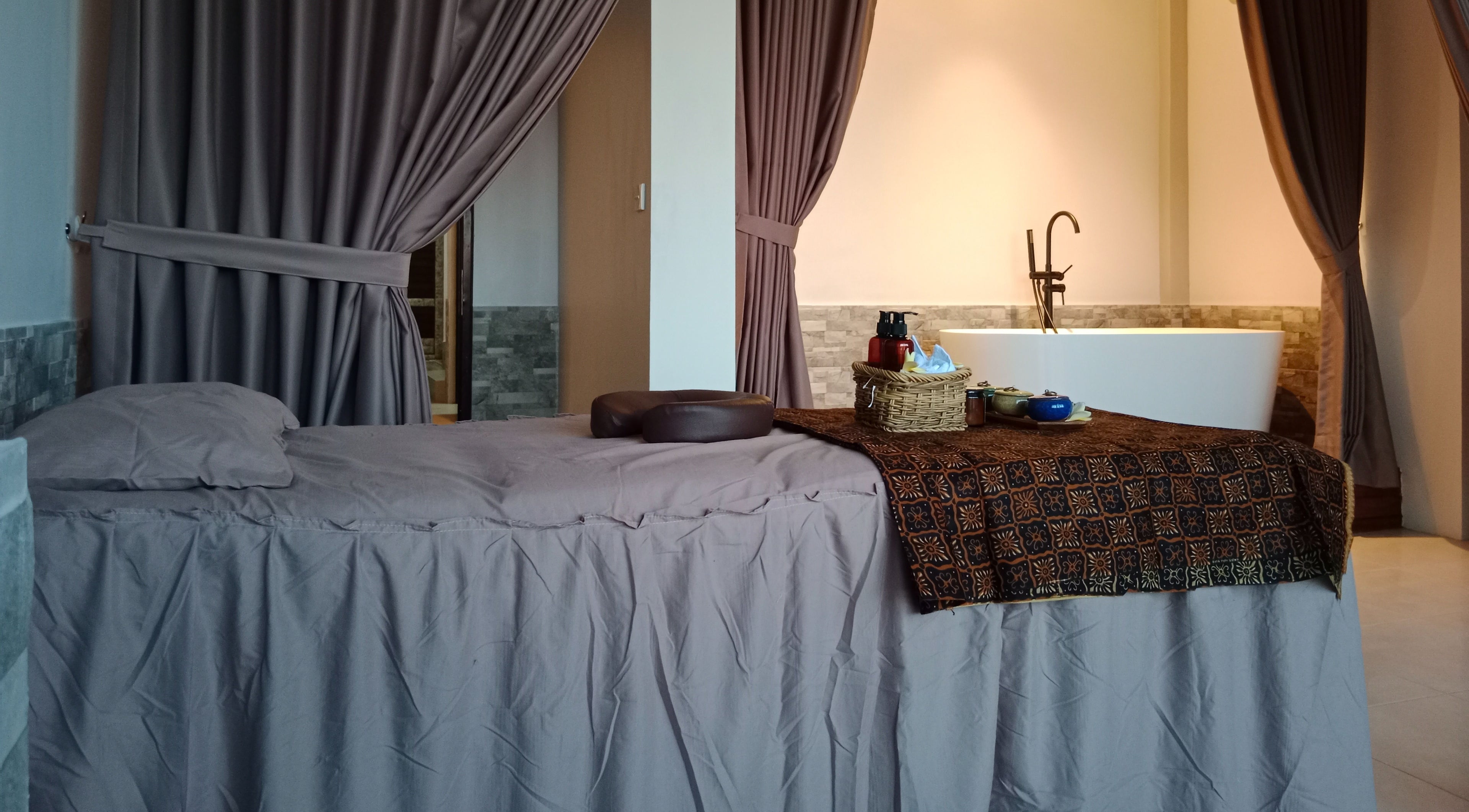 Ruang terapi di Putri Beauty and SPA Seminyak, Bali, Bali, ID dengan tempat tidur pijat dan bak mandi.
