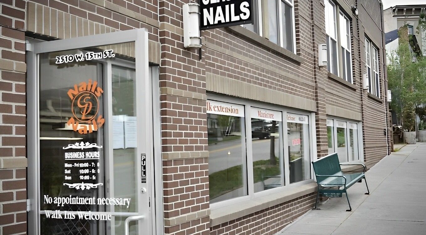 Entrance to Classy Nails in Denver, Colorado with welcoming sign and modern brick exterior.