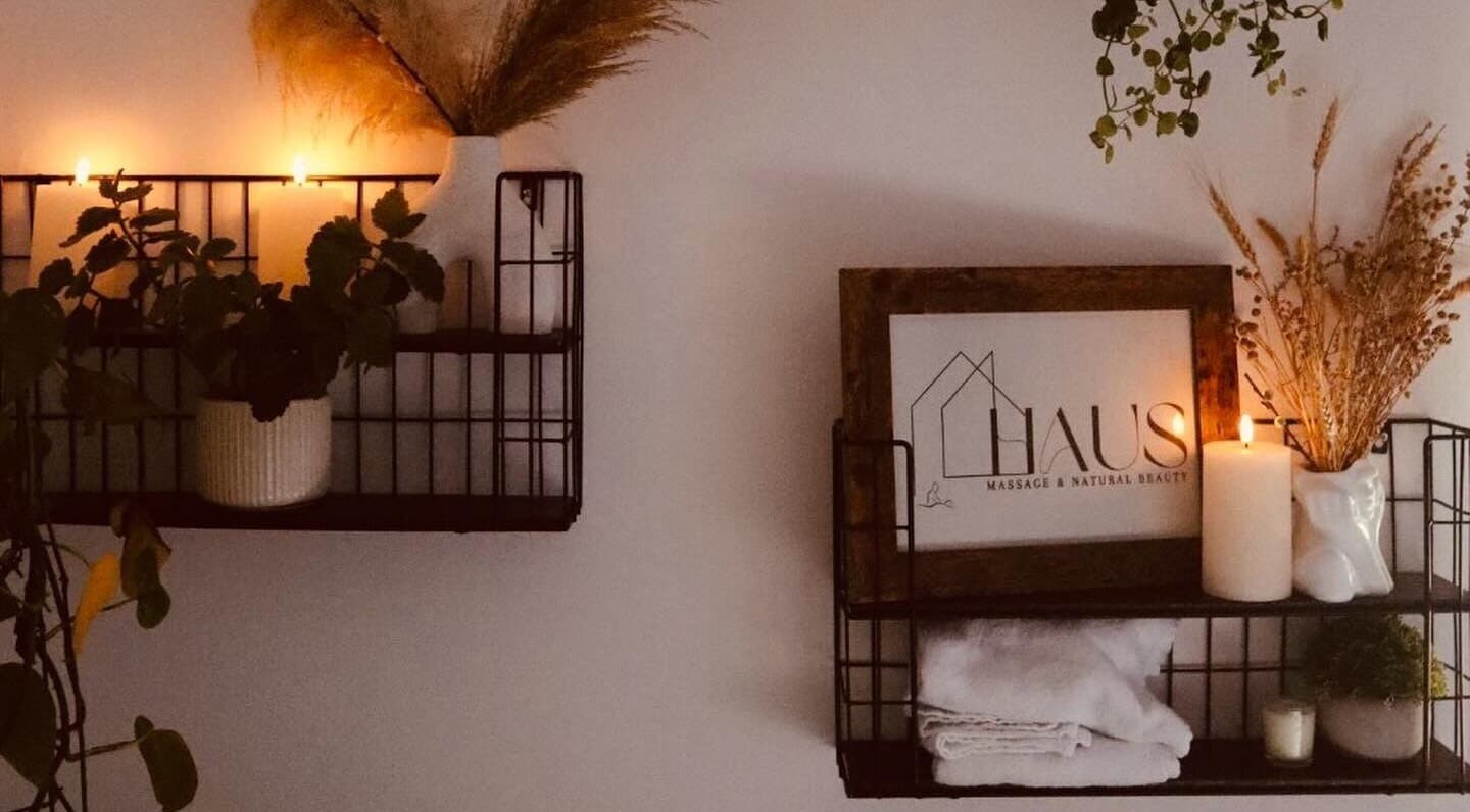 Cozy shelf display at Haus Massage & Natural Beauty in Cardiff, Wales, GB, featuring candles and plants.