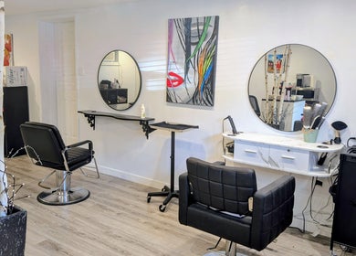 Intérieur moderne du salon L'Avenue coiffure à Sainte-Julie, Canada, CA avec miroirs circulaires et fauteuils noirs.