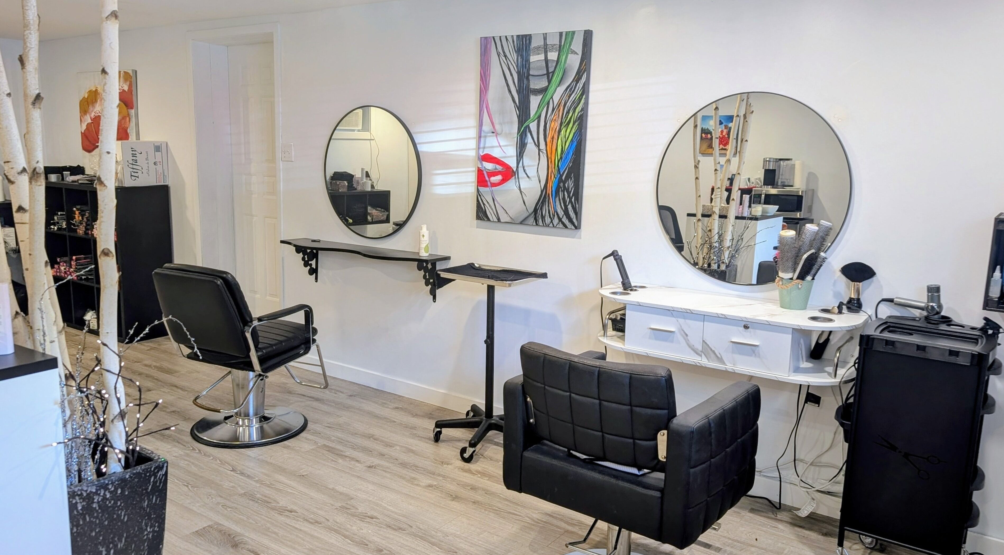 Intérieur moderne du salon L'Avenue coiffure à Sainte-Julie, Canada, CA avec miroirs circulaires et fauteuils noirs.