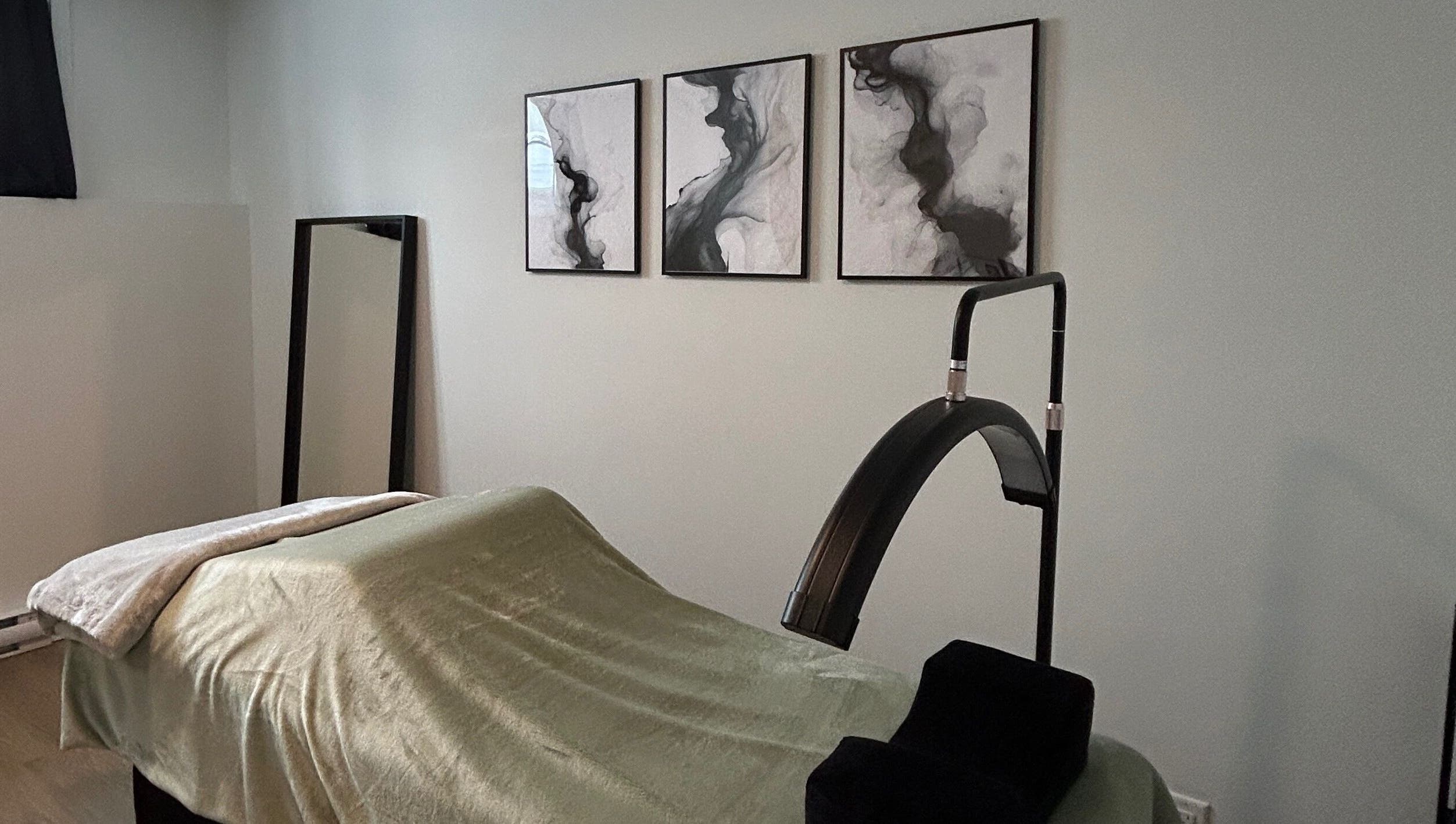 Salle de soins apaisante à Anaïs B. Studio, Yamaska, Québec, CA, avec lit de massage et décoration murale artistique.