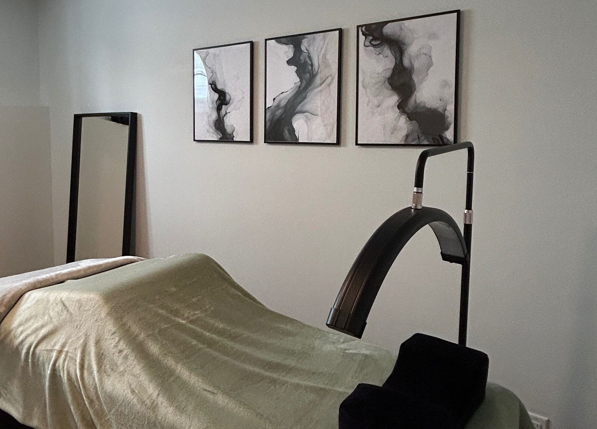 Salle de soins apaisante à Anaïs B. Studio, Yamaska, Québec, CA, avec lit de massage et décoration murale artistique.