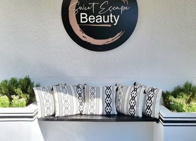 Elegant sitting area at Sweet Escape Beauty, Sandton, Gauteng, ZA, featuring geometric pillows and greenery.