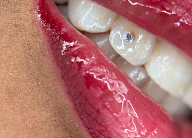 Detalle de labio rojo brillante con diente decorado en sstonegemss, Barcelona, Catalunya, ES.