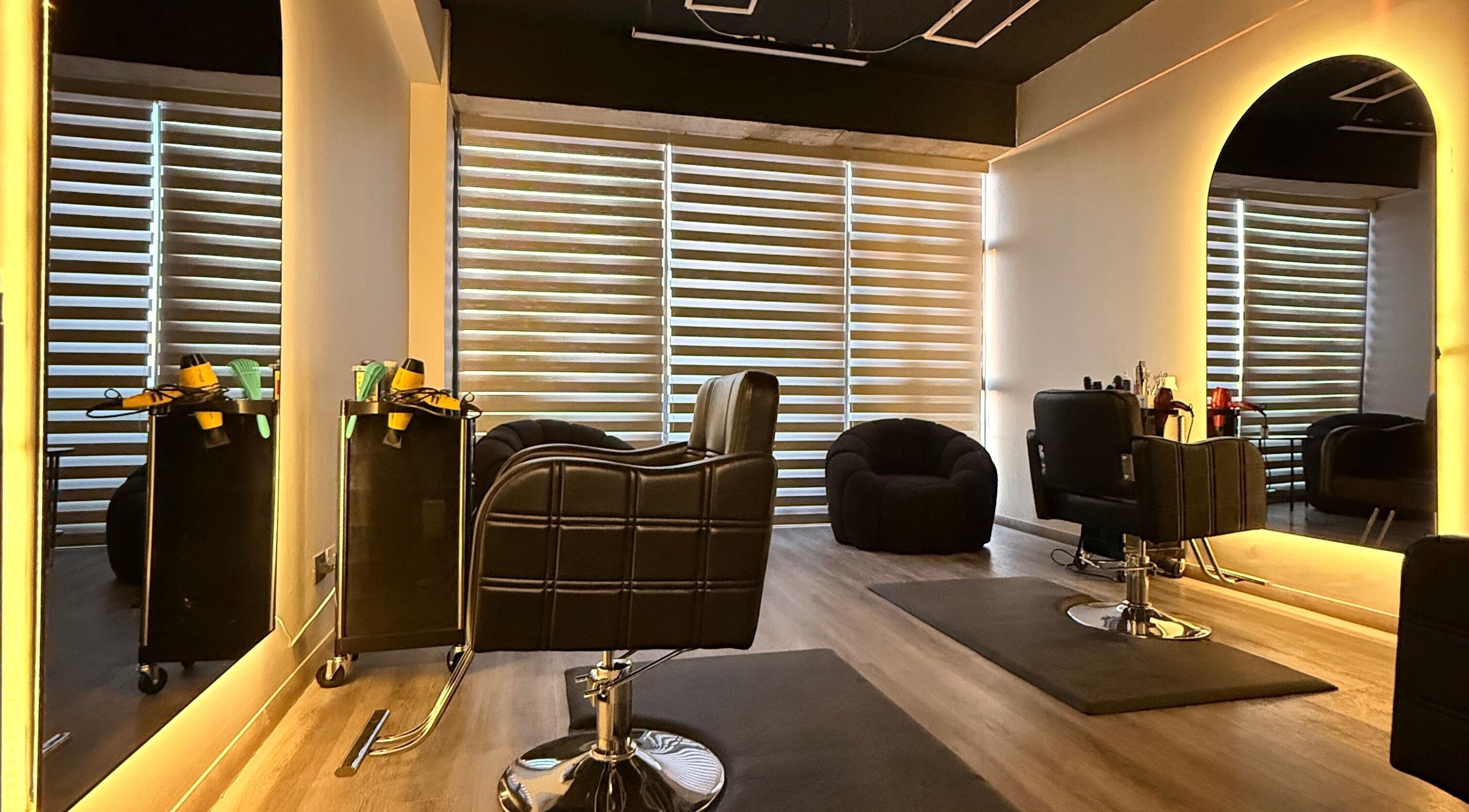 Interior moderno de Peluquería Peñalolen OI en Peñalolén, Región Metropolitana, CL con espejos iluminados y sillas negras.