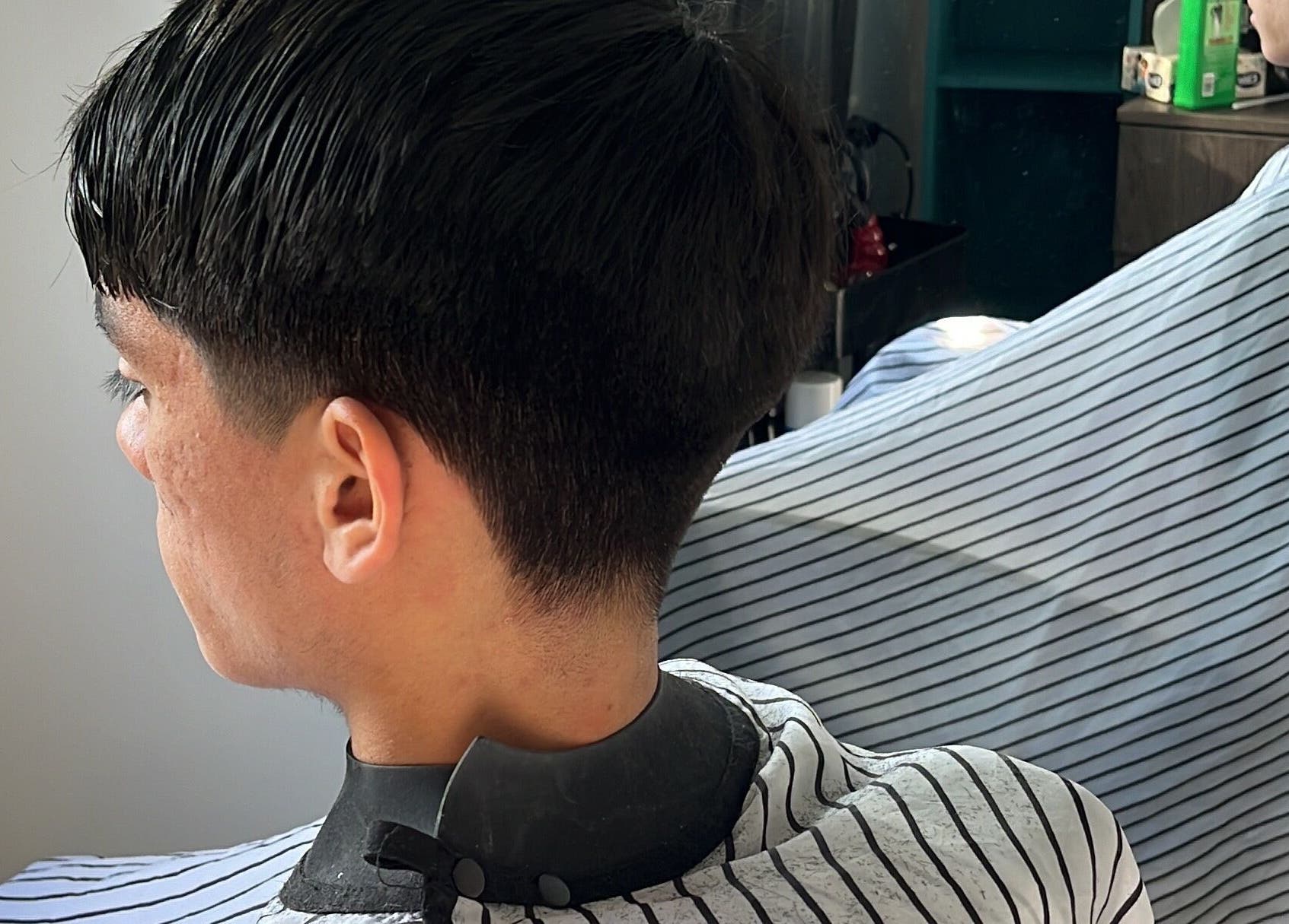 Cliente en Fusión Studio con corte moderno, Macul, Región Metropolitana, CL, reflejado en espejo.