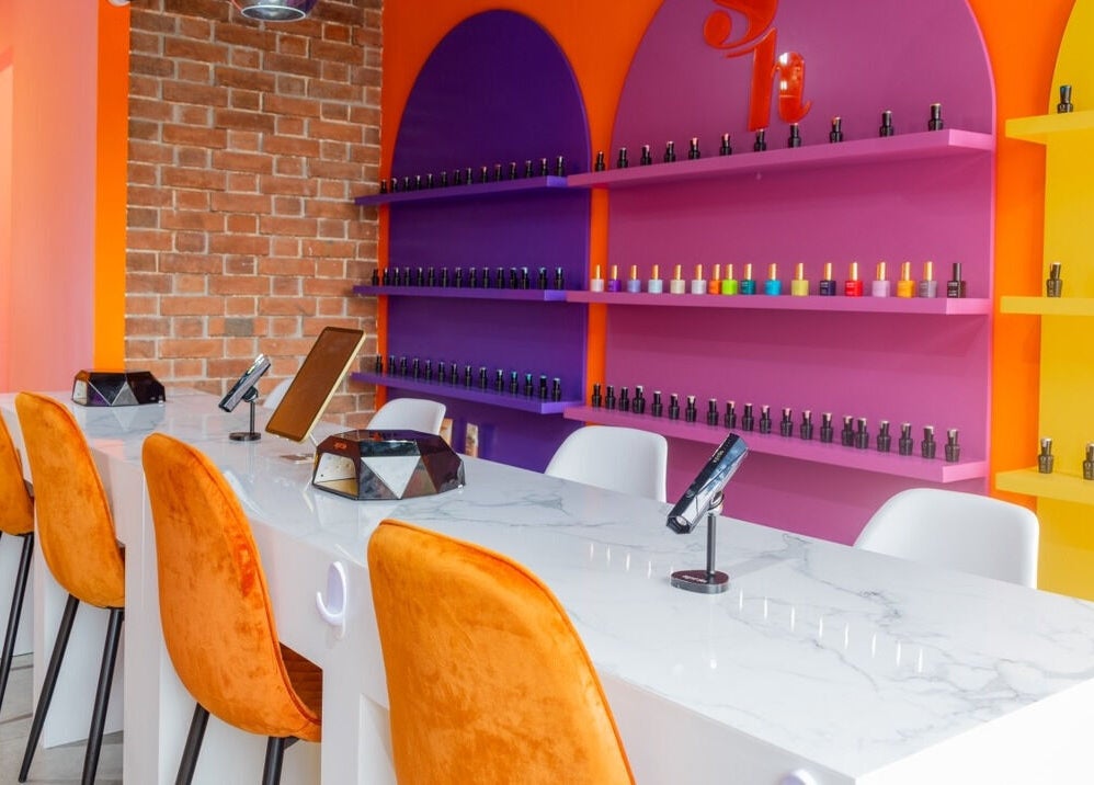 Interior colorido de Sugar Hands en Ciudad De Guatemala, Guatemala, GT con sillas naranjas y estantes vibrantes.