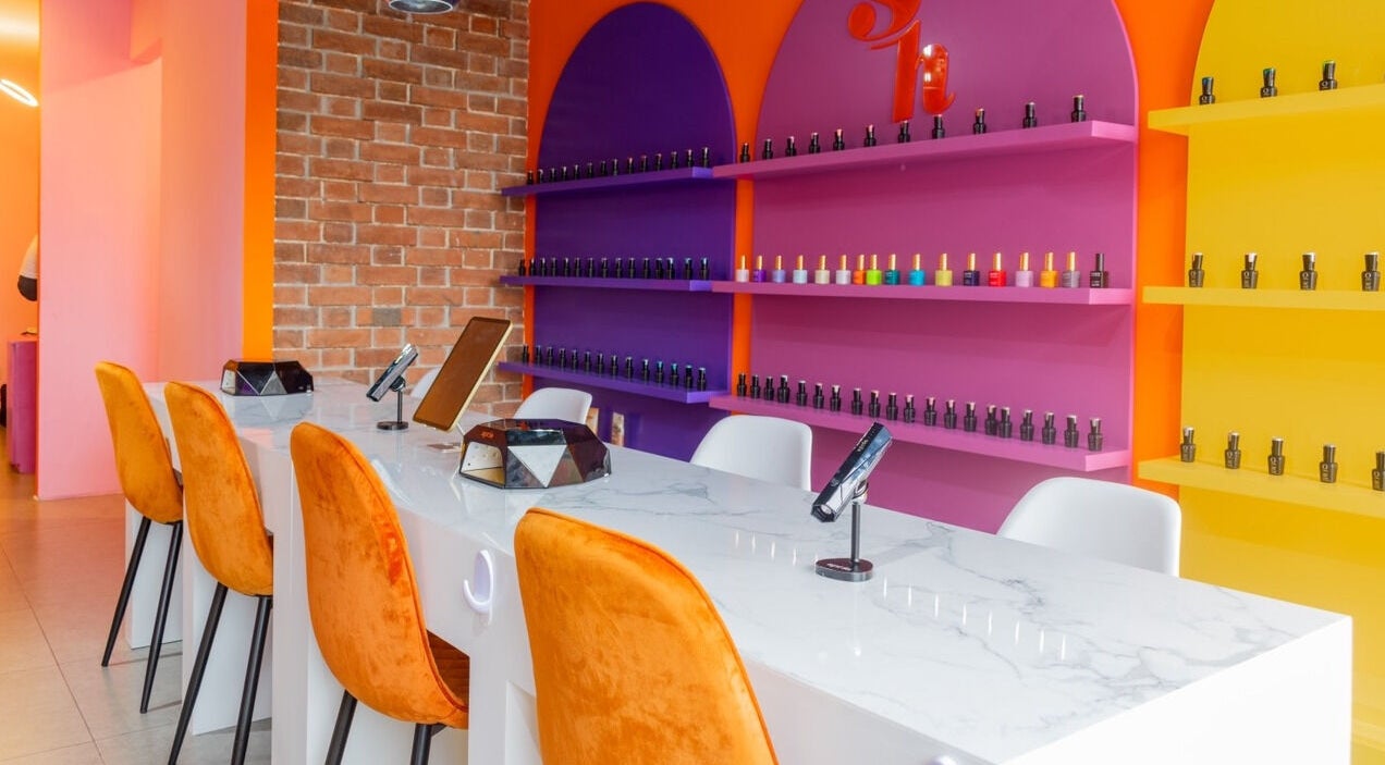 Interior colorido de Sugar Hands en Ciudad De Guatemala, Guatemala, GT con sillas naranjas y estantes vibrantes.