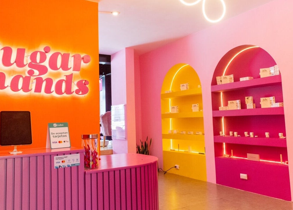 Recepción colorida en Sugar Hands, Ciudad De Guatemala, Guatemala, GT con estantes iluminados y decoración vibrante.