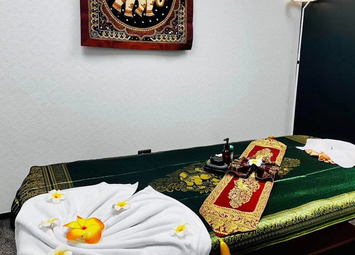 Relaxing massage room at Belmont Thai Massage Station, Auckland, NZ with decorative linens and soft lighting.