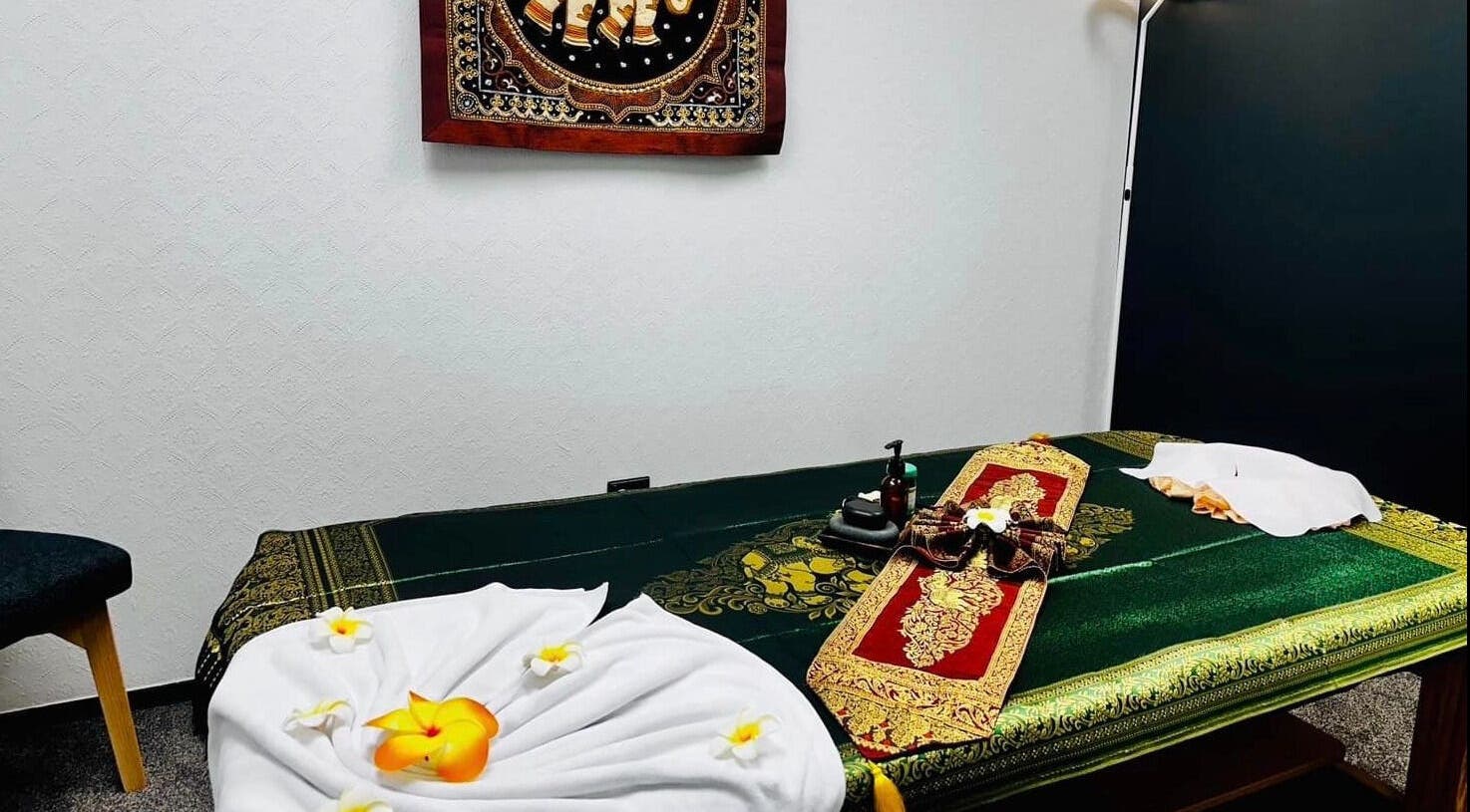 Relaxing massage room at Belmont Thai Massage Station, Auckland, NZ with decorative linens and soft lighting.