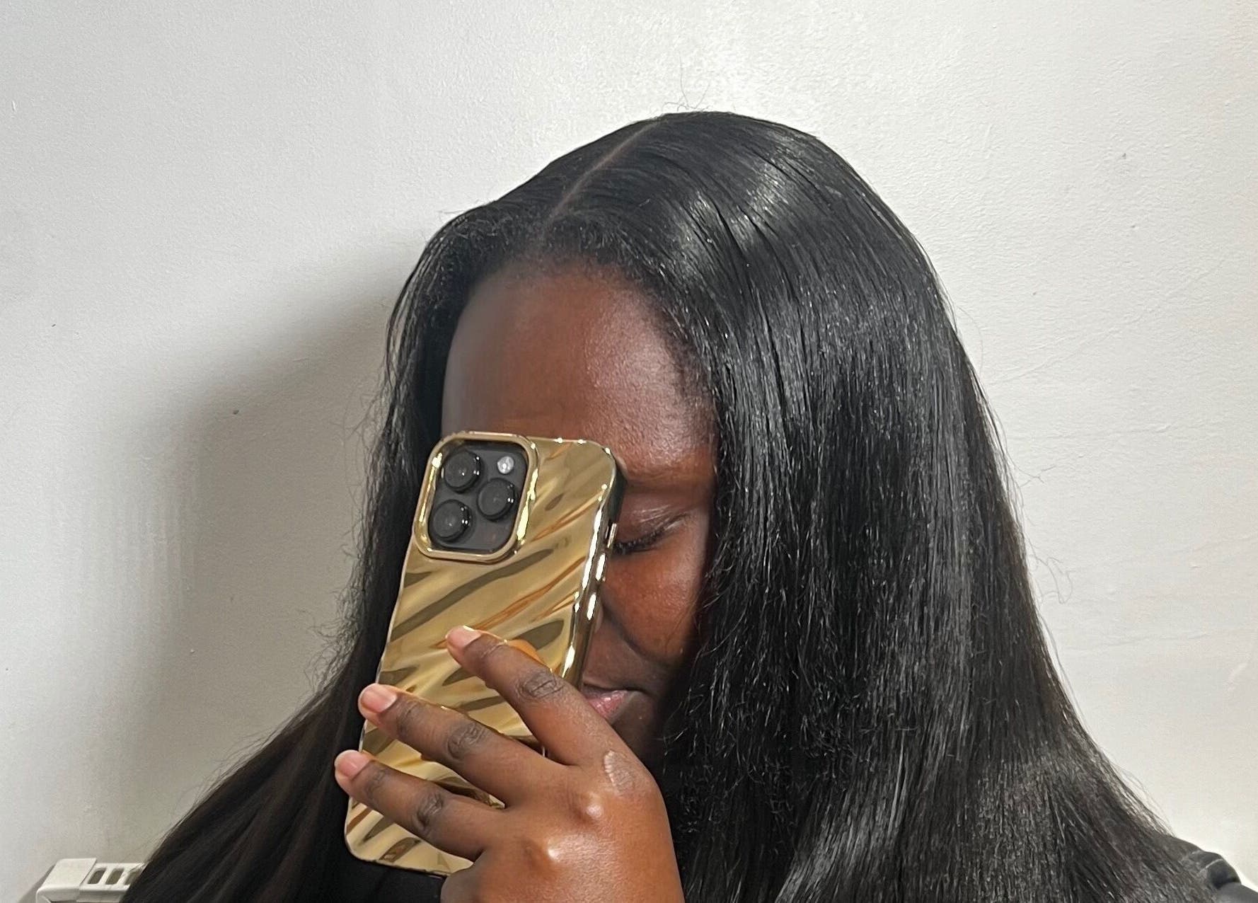 Elegant black-haired woman at Alacedit, Oldham, England, GB, holding a gold smartphone.
