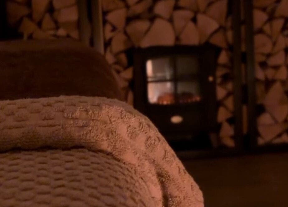 Warm, inviting setup at Näkemiin, Harrold, England, GB with plush towels and a burning fireplace.