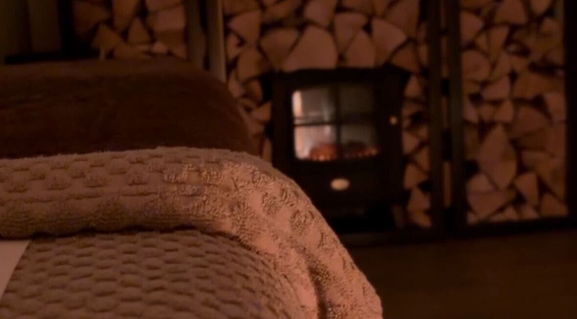Warm, inviting setup at Näkemiin, Harrold, England, GB with plush towels and a burning fireplace.