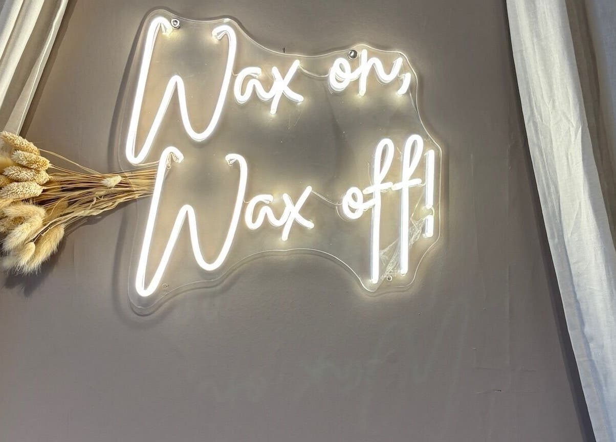 Neon 'Wax on, Wax off!' sign at Näkemiin, Harrold, England, GB, highlighting its stylish decor.