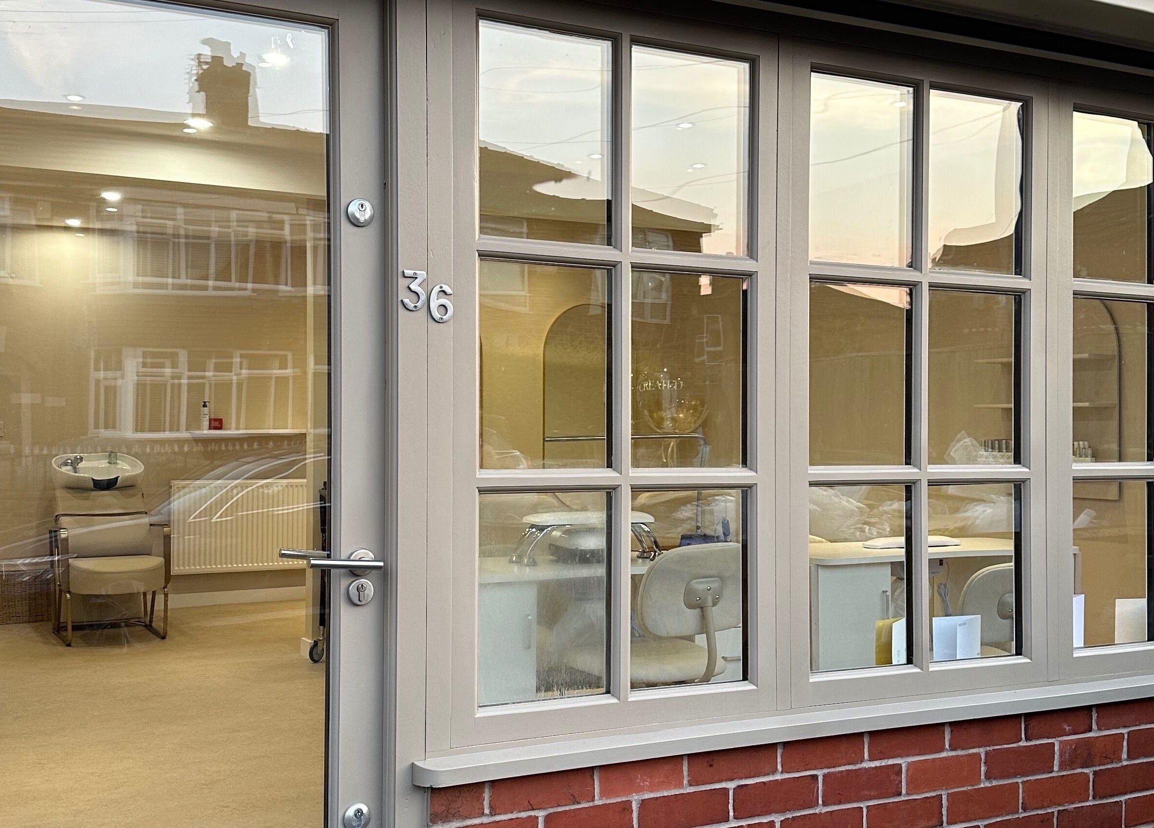 View of Created salon entrance in Swinton, England, GB, showcasing elegant window design and warm interior lighting.