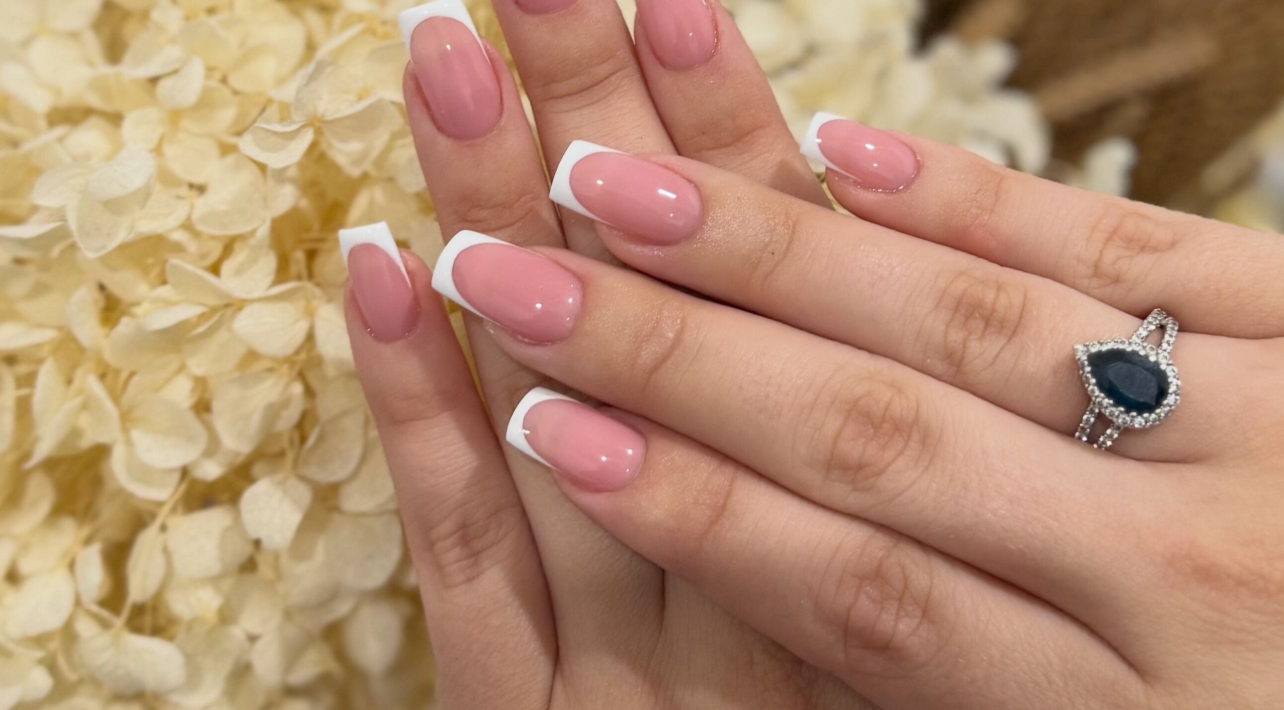 Beautiful French manicure at A Nail Artistry in Casula, New South Wales, AU with a delicate floral background.