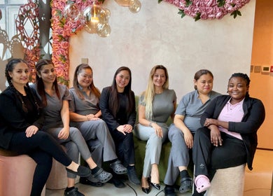 Friendly staff seated at Skinlyft, Dubai, Dubai, AE, with pink floral decor in the background.