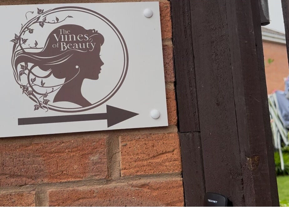 Entrance sign of The Vines Of Beauty with logo at Leeds, England, GB, showing an arrow.