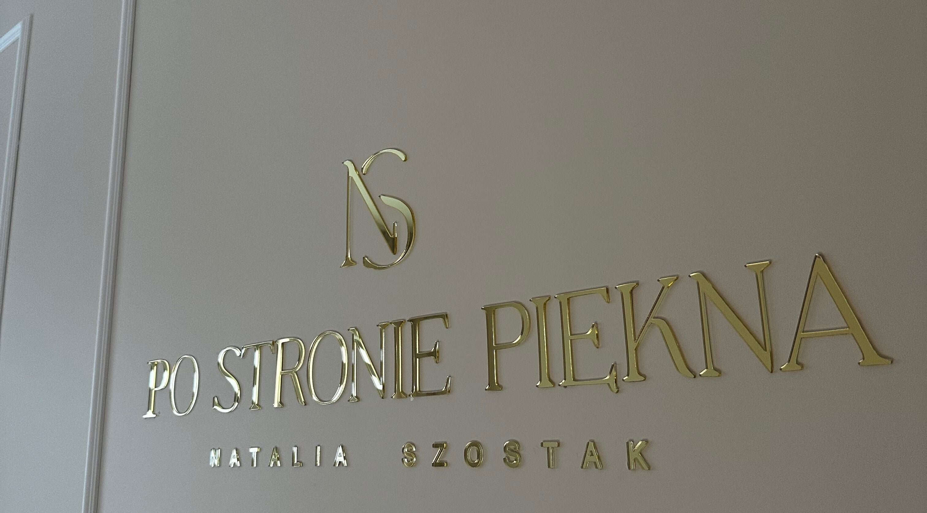 Złote logo Po stronie piękna na ścianie w Olsztynie, Województwo Warmińsko-mazurskie, PL.