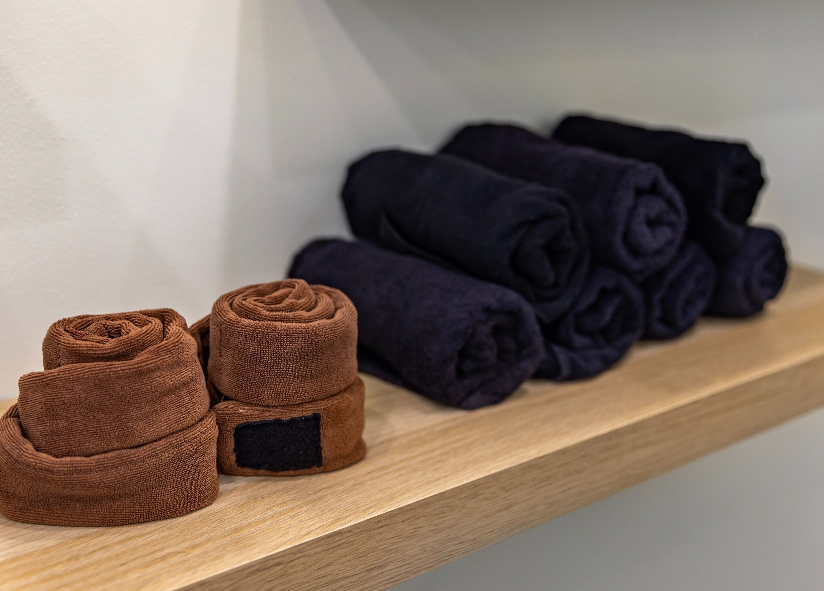 Neatly rolled towels on a wooden shelf at Project Hair Salon, Chippendale, NSW, AU.