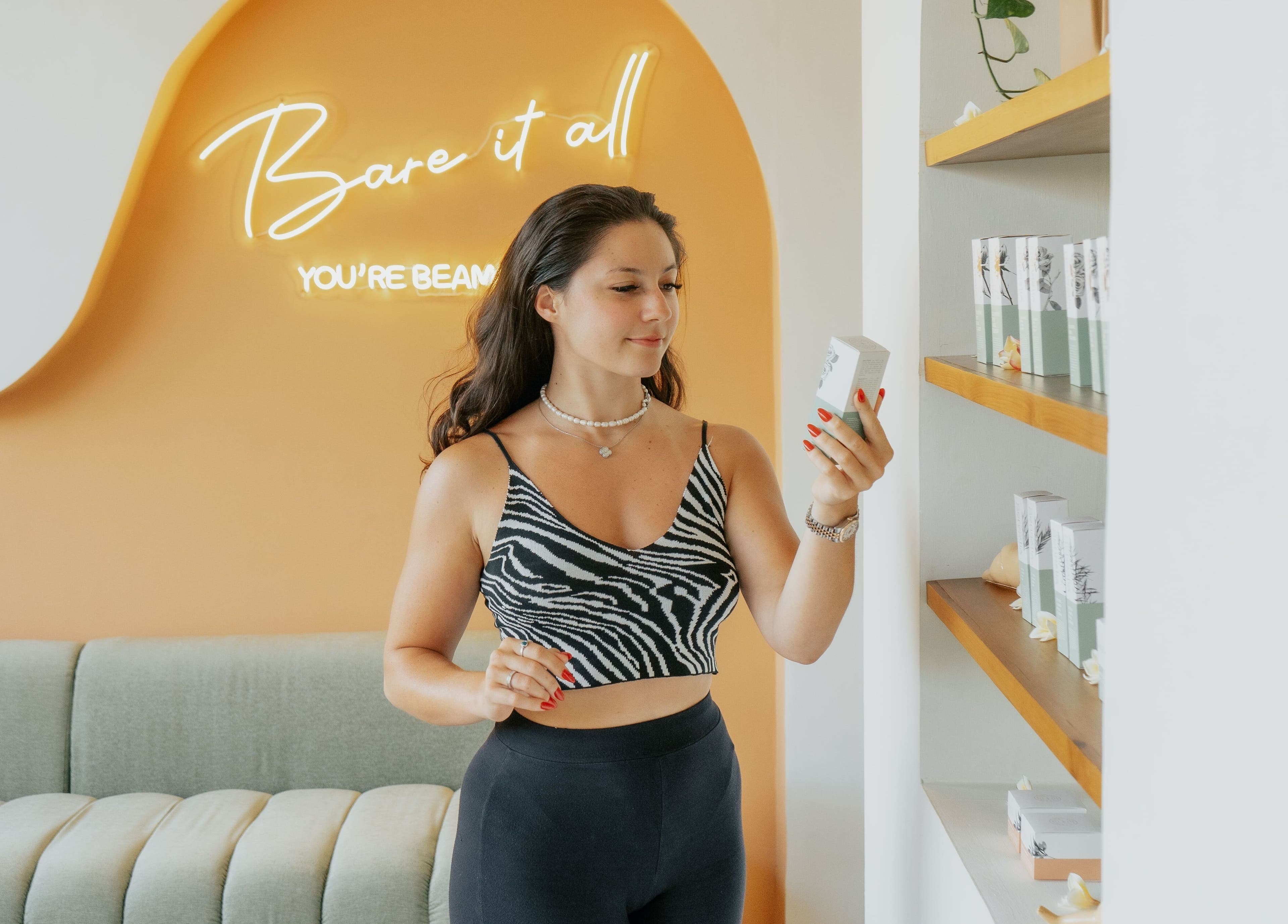 Woman explores beauty products at Beam & Bare, Bali, Bali, ID with stylish neon backdrop.
