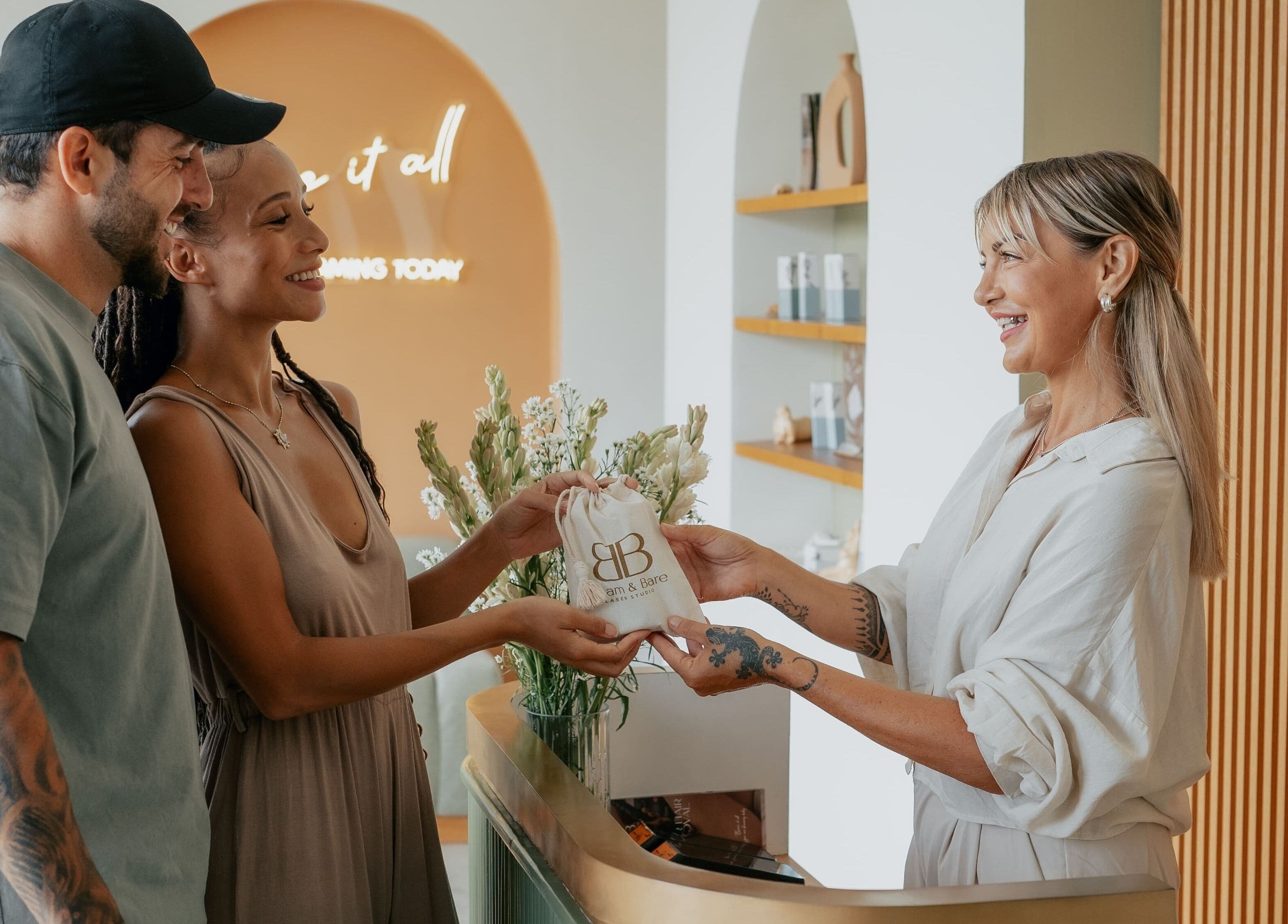 Guests receiving a gift at Beam & Bare in Bali, Bali, ID. Smiling staff and welcoming ambiance.