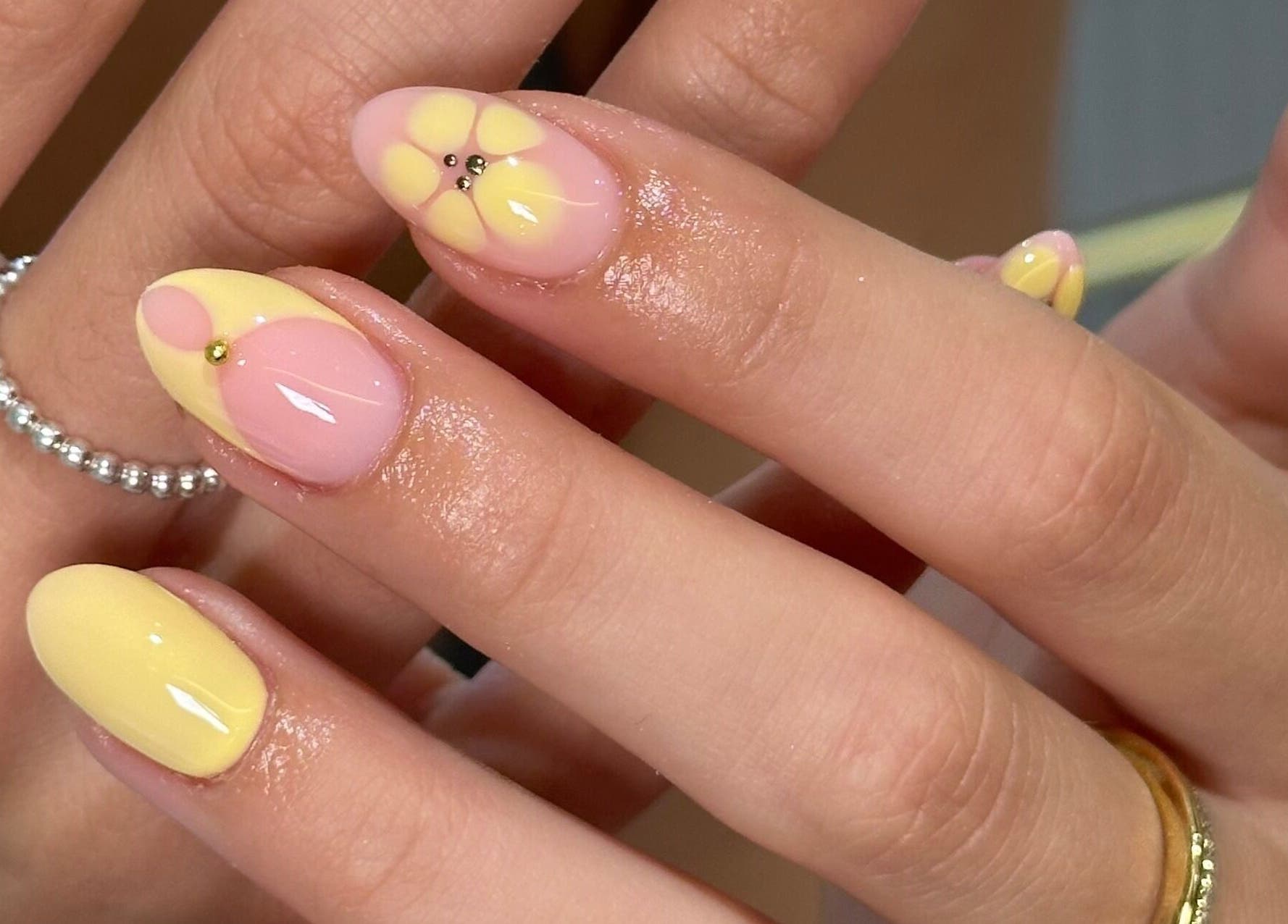 Bright flower nail art at Nails by Ezme, Ashford, England, GB. Features yellow and pink designs on manicured nails.