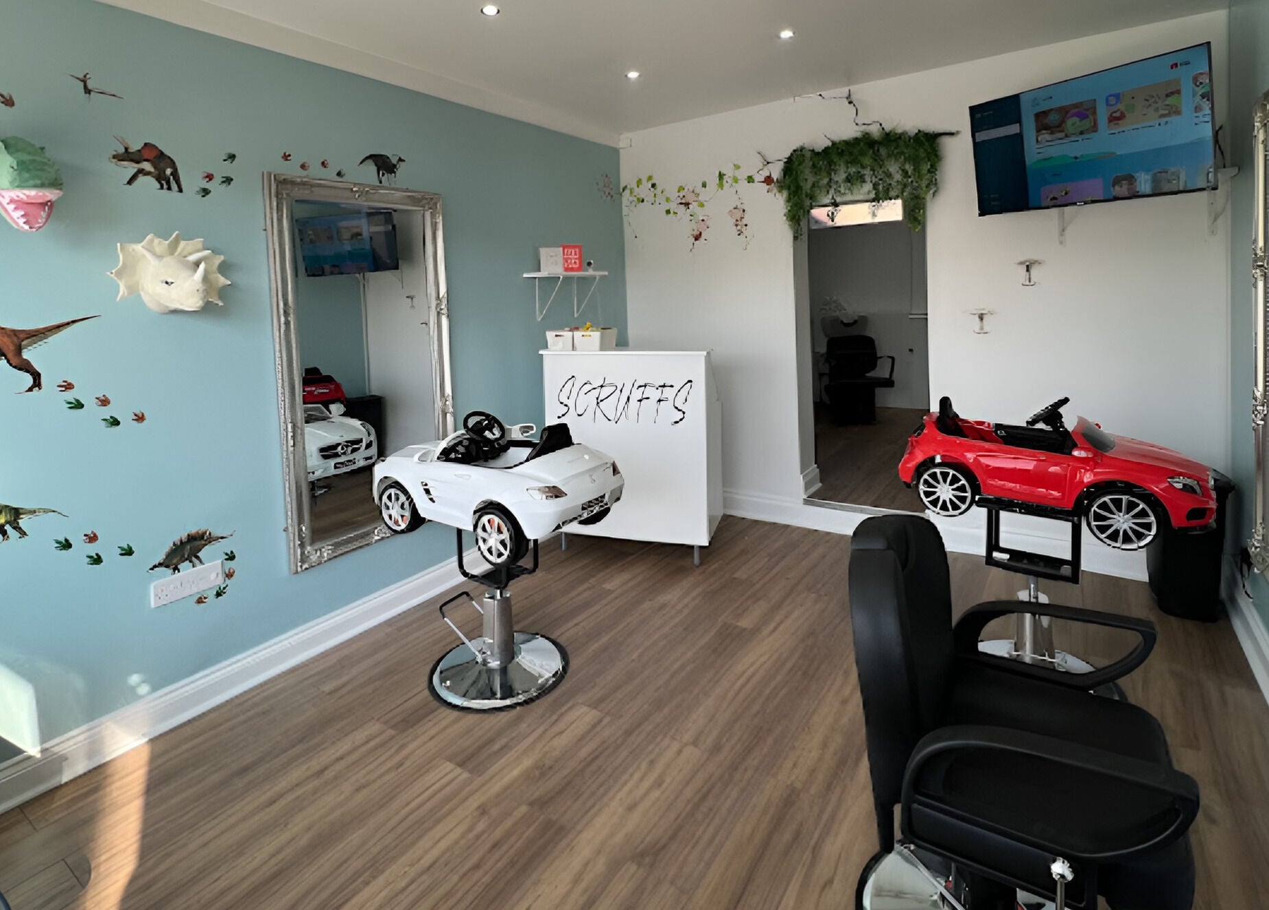 Scruffs children's salon with dinosaur decor and playful car chairs in Litherland, England, GB.