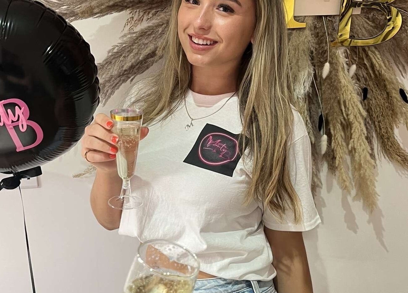 Smiling woman with a drink in hand at Mfb Beauty, Harlow, England, GB, enjoying a festive atmosphere.