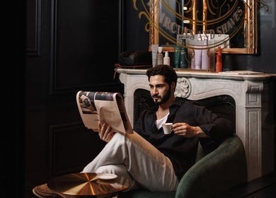 A man relaxes with coffee and reads at Verve Barbershop, Dubai, Dubai, AE.