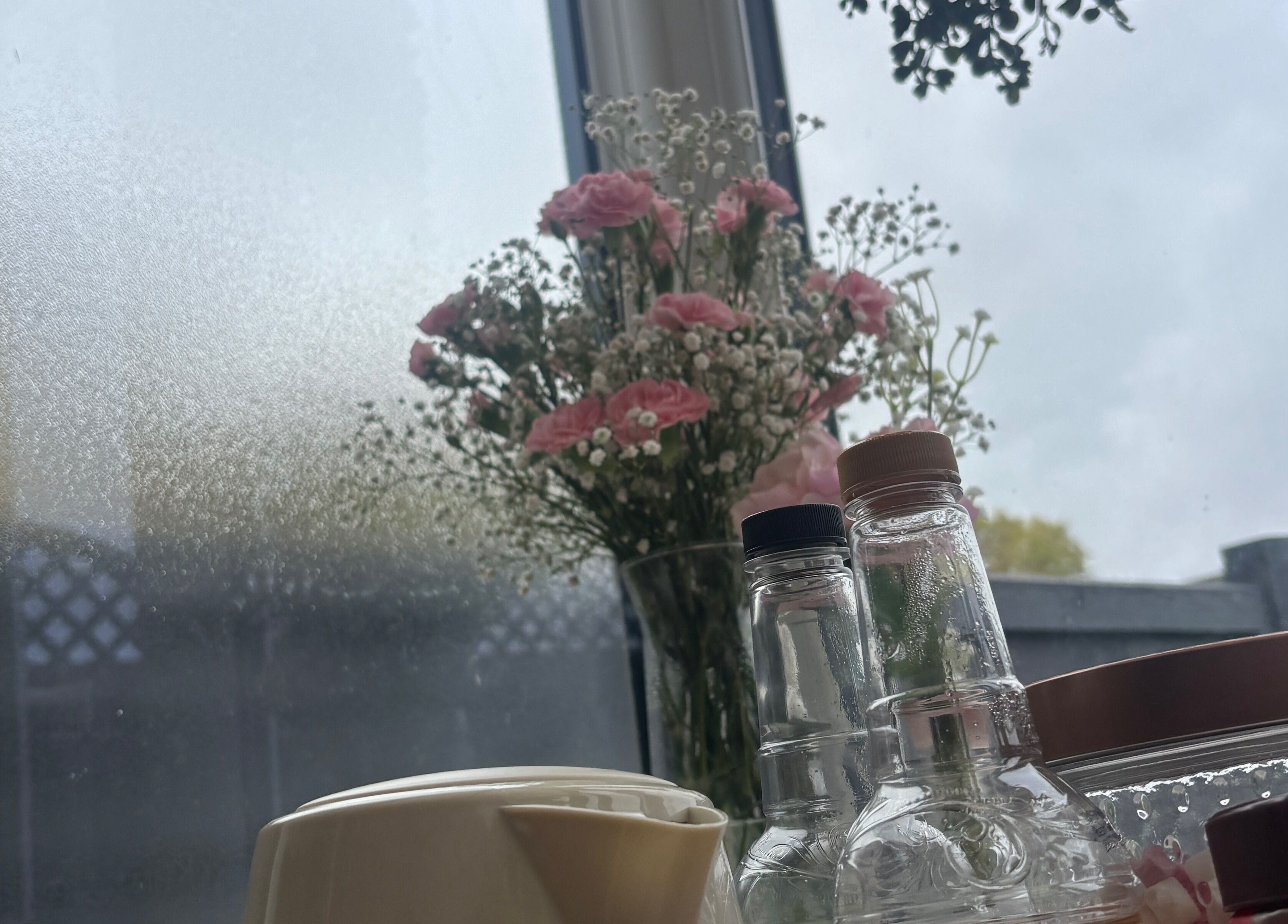 Elegant vase with pink flowers and bottles at The.GloLounge, Wittering, England, GB.