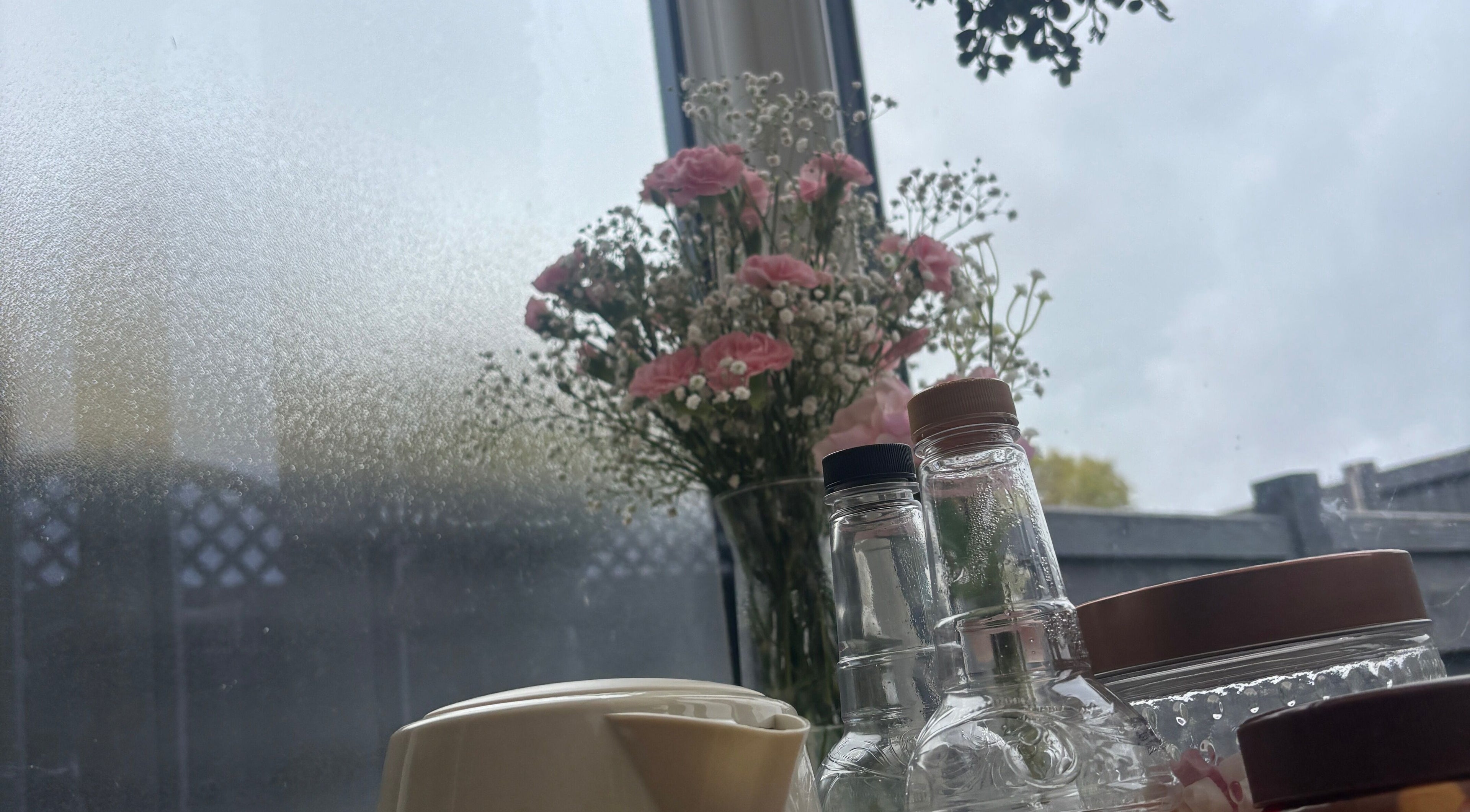 Elegant vase with pink flowers and bottles at The.GloLounge, Wittering, England, GB.