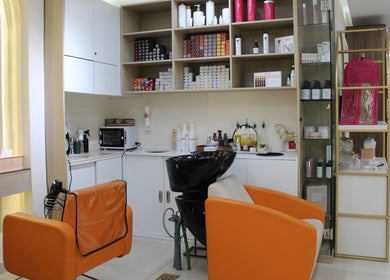 Modern salon interior at Floral Beauty Lounge, Abu Dhabi, AE, featuring stylish orange chairs and shelves.