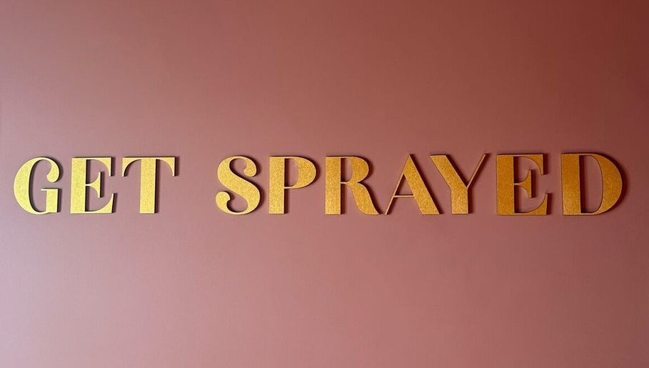 Golden letters on a pink wall spell 'Get Sprayed' at venue in Exeter, England, GB.