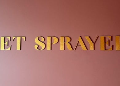 Golden letters on a pink wall spell 'Get Sprayed' at venue in Exeter, England, GB.