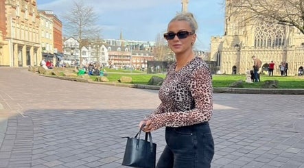 Stylish woman walks near Get Sprayed, Exeter, England, GB with historic architecture in view.
