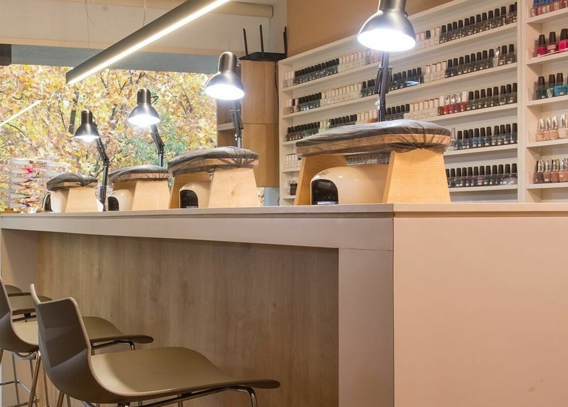 Interior moderno de Nails Bar en Santiago, Región Metropolitana, CL con estantes de esmaltes y sillas elegantes.