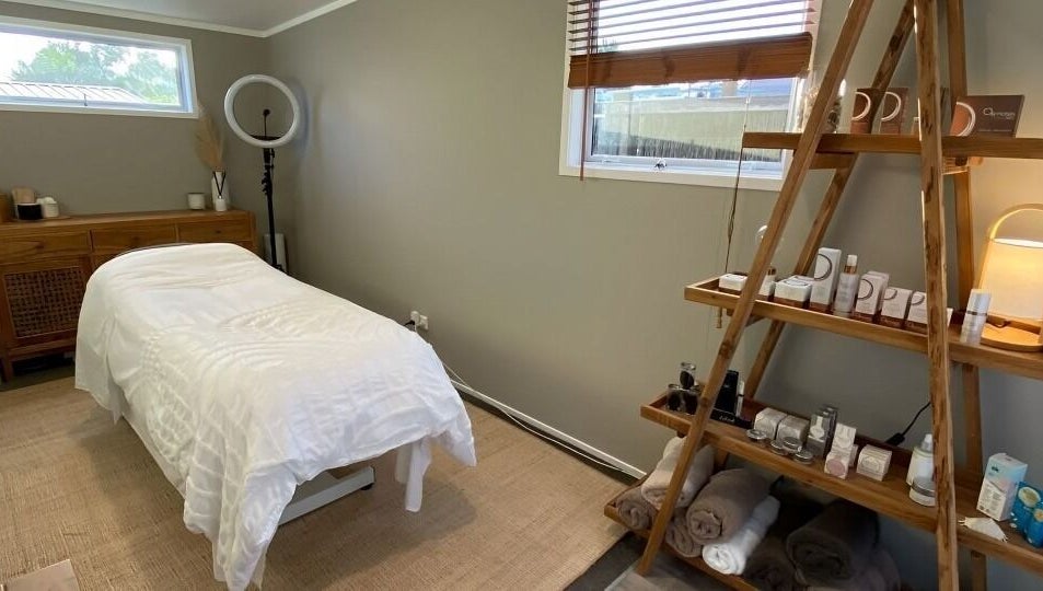 Relaxing treatment room at Tonic Beauté, Auckland, NZ, with cozy bed and wellness products on shelves.