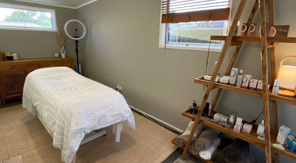 Relaxing treatment room at Tonic Beauté, Auckland, NZ, with cozy bed and wellness products on shelves.
