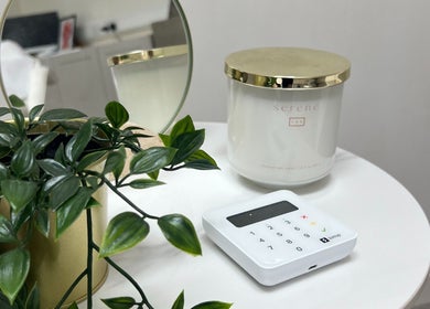 Elegant decor at The Cheshire Retreat Academy Ltd, Hale, England, with a candle and plant on a white table.
