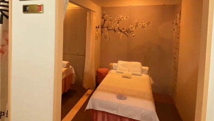 Tranquil massage room at RoyalwayTCM 御道中医 in Singapore, Singapore, SG with a cozy bed and cherry blossom decor.