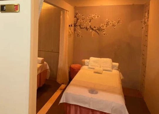 Tranquil massage room at RoyalwayTCM 御道中医 in Singapore, Singapore, SG with a cozy bed and cherry blossom decor.