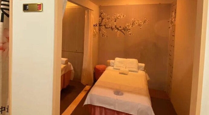 Tranquil massage room at RoyalwayTCM 御道中医 in Singapore, Singapore, SG with a cozy bed and cherry blossom decor.