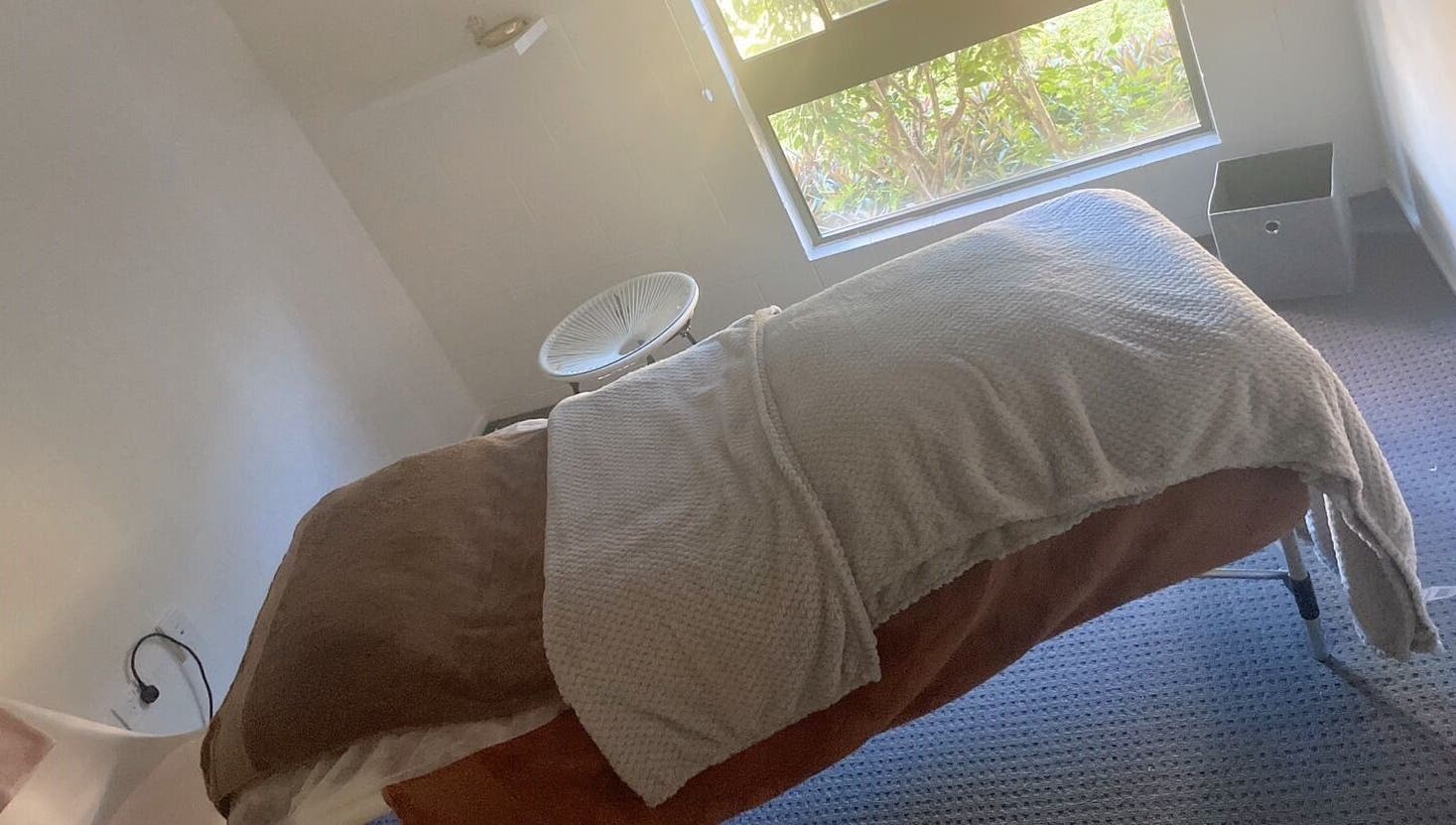 Cozy massage room at ＷＡＲＭ 1.3 in Kirwan, Queensland, AU with a plush bed and sunlight streaming through the window.