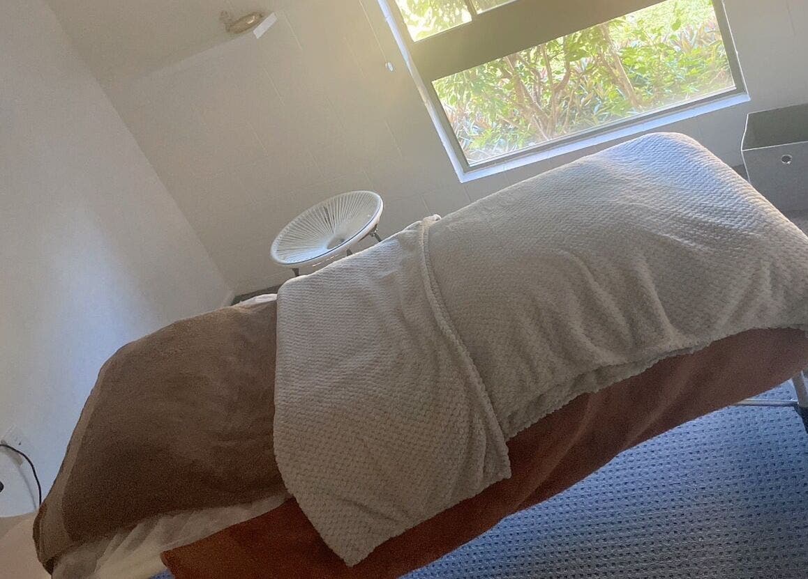 Cozy massage room at ＷＡＲＭ 1.3 in Kirwan, Queensland, AU with a plush bed and sunlight streaming through the window.